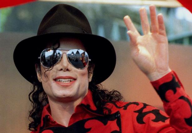 Michael Jackson mit Hut und Sonnenbrille winkt in die Kamera.