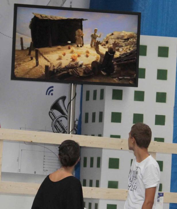 Zwei Personen betrachten einen Bildschirm mit einer Stop-Motion-Szene.