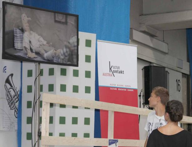 Auf einem Bildschirm ist eine Stop-Motion-Figur mit Gipsbein zu sehen.