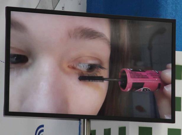 Eine Frau trägt Wimperntusche auf ihre Wimpern auf.