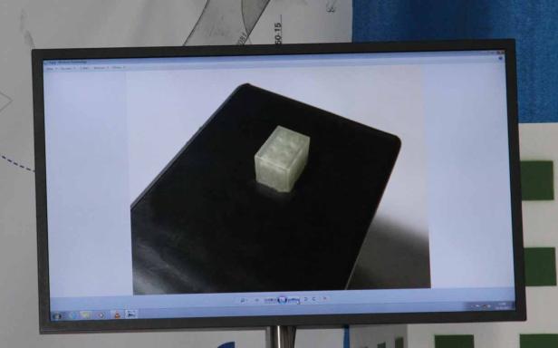 Ein Bildschirm zeigt ein Foto eines transparenten Legosteins auf einer schwarzen Oberfläche.