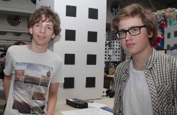 Zwei junge Männer stehen vor einem Tisch mit technischen Geräten.