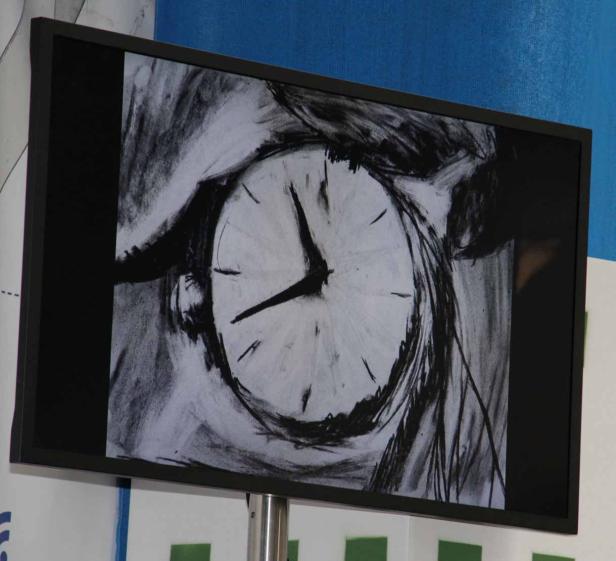 Ein Bildschirm zeigt eine Kohlezeichnung einer Uhr.