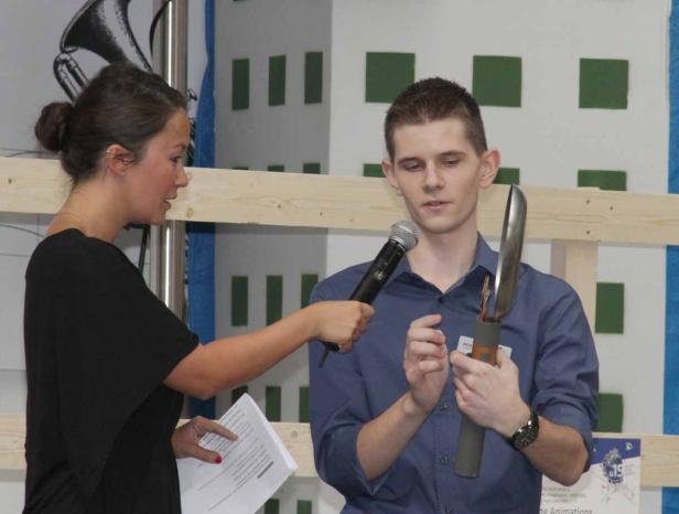 Eine Frau interviewt einen jungen Mann, der ein ungewöhnliches Gerät in den Händen hält.