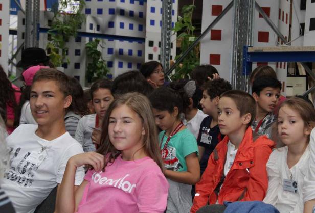 Eine Gruppe von Kindern sitzt aufmerksam in einem Raum.