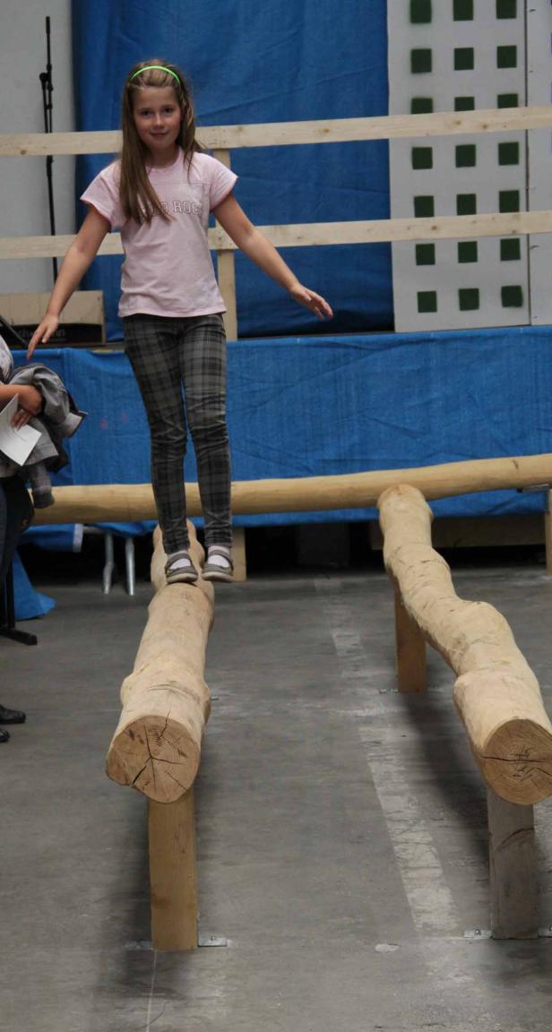 Ein junges Mädchen balanciert auf einem Baumstamm.