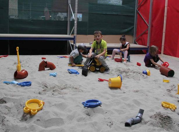 Kinder spielen mit Sandspielzeug in einem Sandkasten.