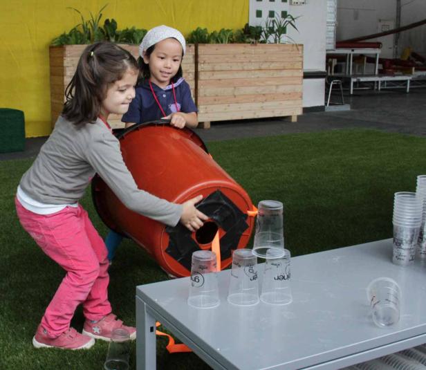 Zwei Mädchen spielen ein Spiel mit einem Fass und Plastikbechern.