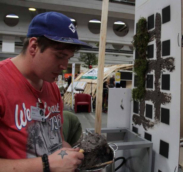 Ein Künstler gestaltet ein Gebäude mit Erde und Moos.