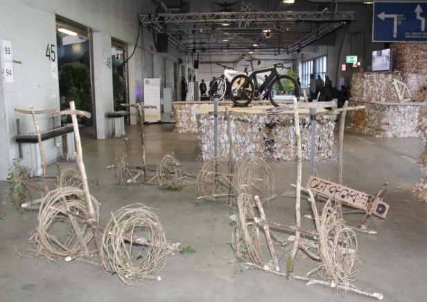 Eine Installation mit Fahrrädern aus Ästen und Reisig in einer Ausstellungshalle.
