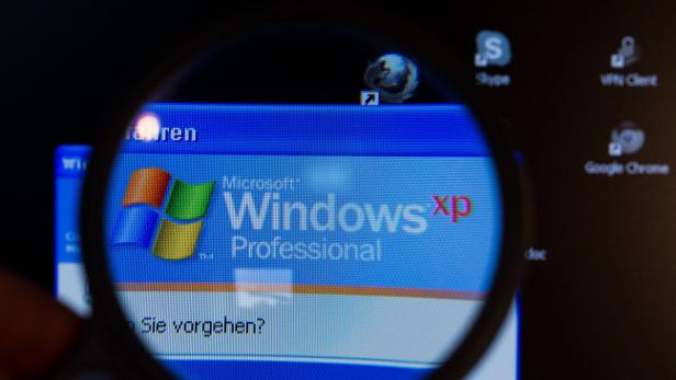 Ein Bildschirm mit dem Windows XP Professional-Logo wird durch eine Lupe betrachtet.