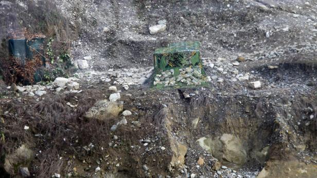 Zwei getarnte Unterstände stehen an einem steinigen Hang.