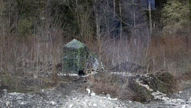 Ein mit Tarnnetz bedecktes Zelt steht am Rande eines Waldes.