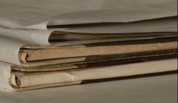 Ein Stapel alter, gebundener Bücher, teilweise mit Papier umwickelt.