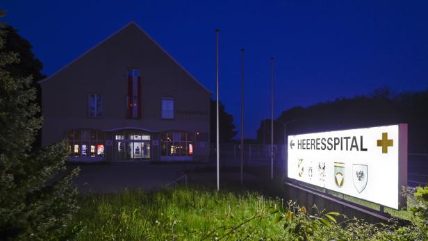 Im Heeresspital werden das finnische Paar und Dominik Neubauer derzeit von den Medien abgeschottet Bei Nachtaufnahme zeigt ein Schild den Weg zum Heeresspital mit verschiedenen Wappen.