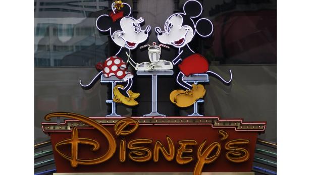 Leuchtende Mickey- und Minnie-Maus-Figuren sitzen an einem Tisch über dem „Disney's“-Schild.