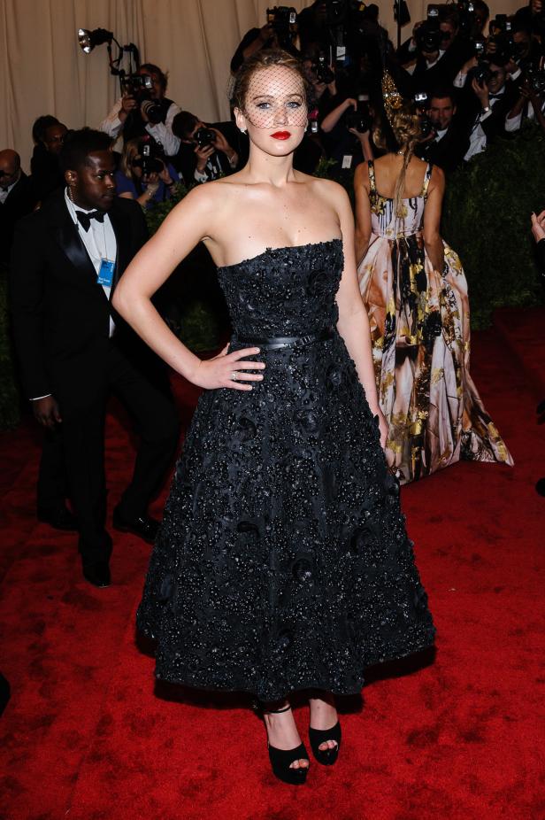 Jennifer Lawrence in einem schwarzen Kleid auf dem roten Teppich, umgeben von Fotografen.