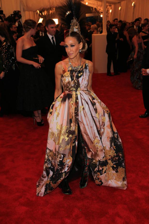 Sarah Jessica Parker auf dem roten Teppich mit einem auffälligen Kleid und Kopfschmuck.