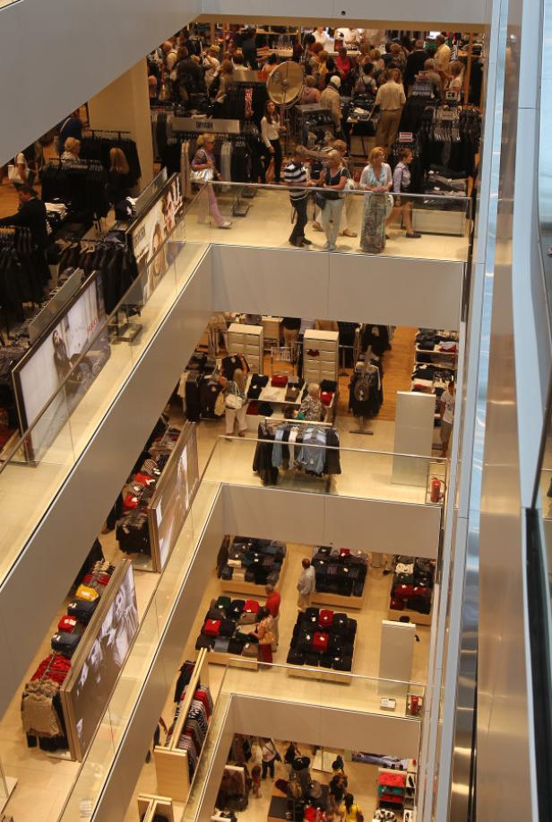 Mehrere Etagen eines Kaufhauses mit Kunden und Bekleidungsauslagen.