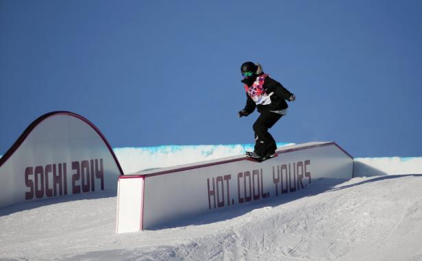 Eine Snowboarderin fährt auf einer Rampe mit der Aufschrift „HOT. COOL. YOURS“ in Sotschi 2014.
