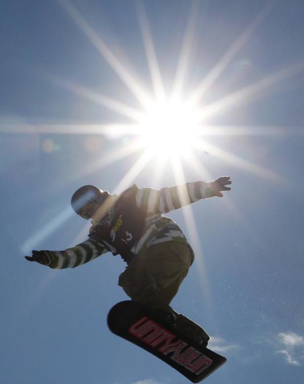 Ein Snowboarder springt vor strahlendem Himmel.