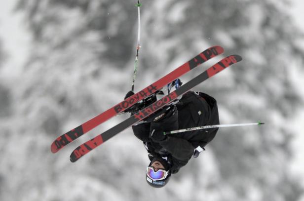 Ein Skifahrer macht einen Trick in der Luft vor einem verschneiten Hintergrund.