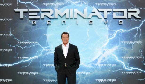 Arnold Schwarzenegger posiert vor einem „Terminator Genisys“-Poster.