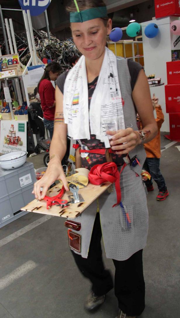 Eine Frau mit Werkzeugen und einem Getränk auf einem Tablett bei einer Veranstaltung.