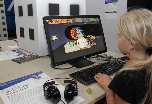 Ein junges Mädchen spielt ein Computerspiel mit einem Wissenschaftler und einem Roboter im Weltraum.