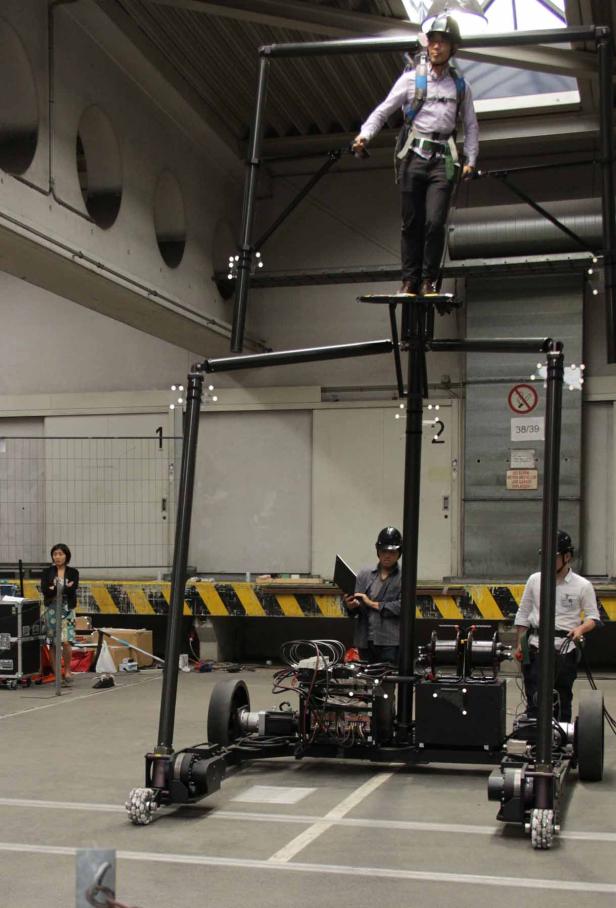 Eine Person steht auf einer Plattform, die auf einem fahrbaren Roboter montiert ist.