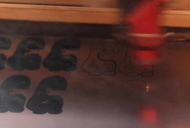 Ein Laser schneidet Dinosaurier-Formen aus einem Material.