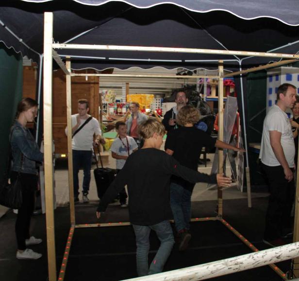 Mehrere Personen stehen und gehen in einem Raum mit einer Holzrahmenkonstruktion.