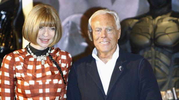 Anna Wintour und Giorgio Armani posieren vor einer Batman-Figur.