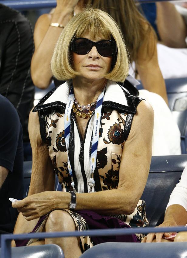 Anna Wintour, mit Sonnenbrille, sitzt bei einem Tennismatch im Publikum.