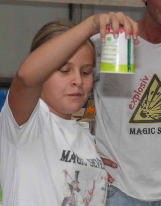 Ein Mädchen hält einen Becher mit erhobenem Arm hoch.