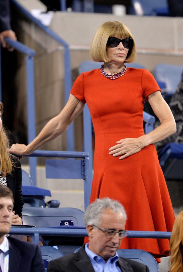 Anna Wintour in einem roten Kleid und einer Halskette bei einem Tennismatch.