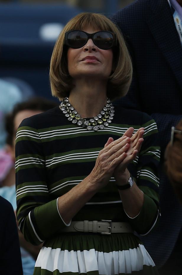 Anna Wintour mit Sonnenbrille und auffälliger Halskette klatscht Beifall.