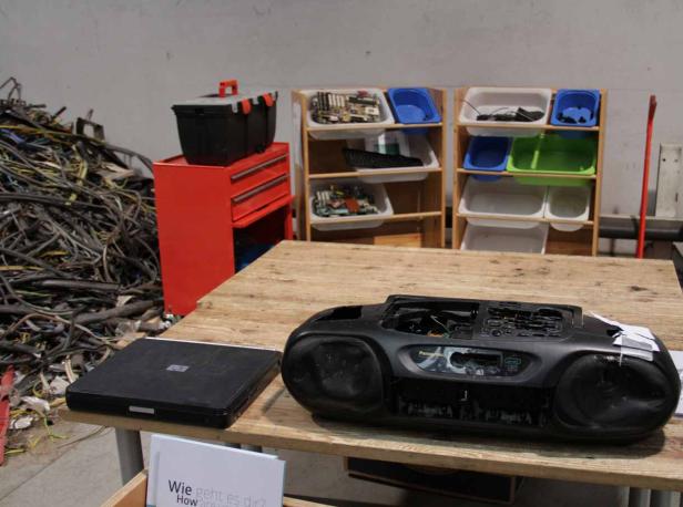 Ein Tisch mit Elektroschrott, darunter ein Laptop und ein zerlegter Ghettoblaster.