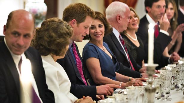 Prinz Harry sitzt bei einem formellen Abendessen neben anderen Gästen.
