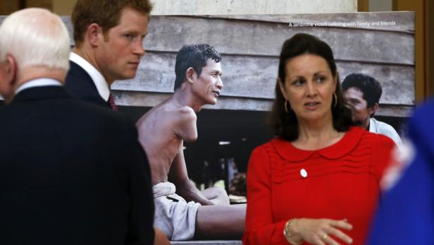 Prinz Harry und eine Frau betrachten ein Foto eines Minenopfers mit seiner Familie.