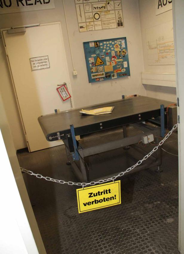 Ein Förderband ist mit einer Kette und einem „Zutritt verboten!“-Schild abgesperrt.