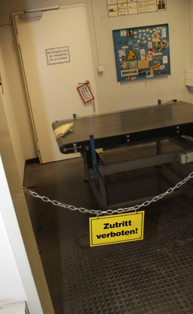Ein Förderband ist mit einer Kette und einem „Zutritt verboten!“-Schild abgesperrt.