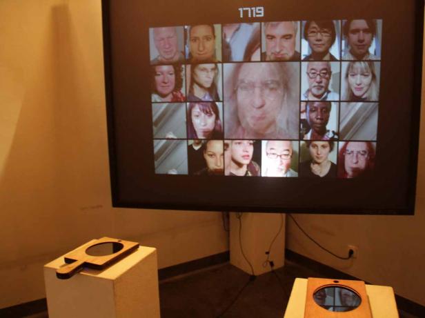 Eine Videoinstallation mit einer Collage von Gesichtern auf einem Bildschirm.