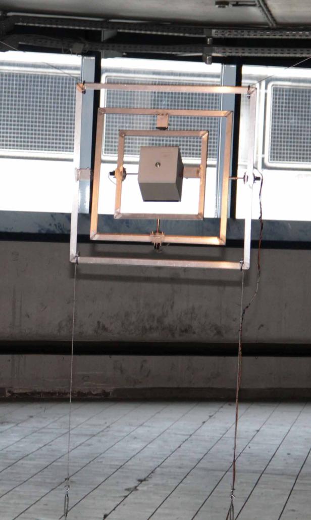 Eine Apparatur mit einem Würfel in der Mitte hängt von der Decke.