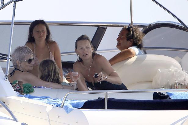 Kate Moss und andere Personen entspannen auf einer Yacht mit Getränken.