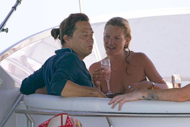Kate Moss und ein Mann entspannen mit Getränken auf einer Yacht.