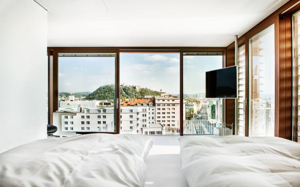 Blick aus einem Hotelzimmer auf Graz mit dem Schlossberg im Hintergrund.