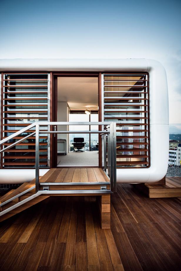 Ein modernes, weißes Gebäude mit Holzverkleidung und einer Terrasse mit Blick auf die Stadt.