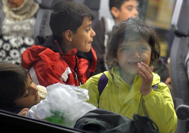 Mehrere Kinder sitzen oder liegen, möglicherweise in einem Bus oder Zug.