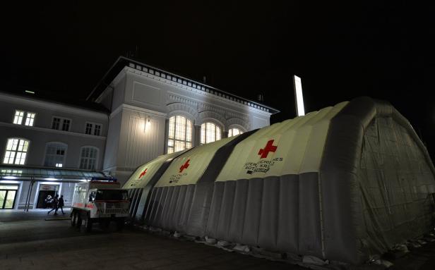 Ein Zelt des Österreichischen Roten Kreuzes steht nachts vor einem Gebäude.